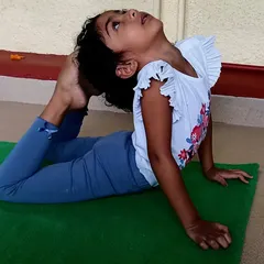 A child demonstrates impressive flexibility in the bow pose. I encourage each child to explore what their body can do in a non-competitive and supportive environment.