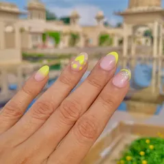 Capturing the royal grandeur of Udaipur with these nails. This design features a neon yellow French tip with polka dots, perfect for a picturesque vacation.