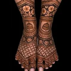 An elegant feet mehndi design featuring floral bands and traditional jhumka (bell) motifs. The dark stain looks stunning against the skin.