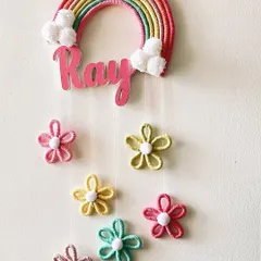 This is a still image of the custom 'Ray' nameplate, highlighting the bright colors of the rainbow, the fluffy pom-pom clouds, and the handcrafted flower details.