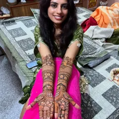 A smiling bride proudly presents her full-arm Rajasthani mehendi. The design is filled with traditional floral and animal motifs.