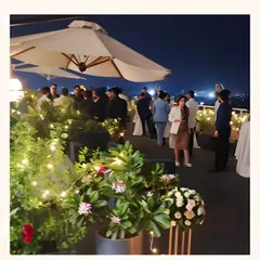 Guests mingling at a sophisticated rooftop party at night. Our setup includes large umbrellas and fairy lights to create a comfortable and festive atmosphere.