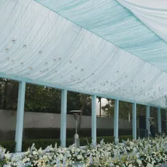 The walkway for the Anand Karaj ceremony is lined with lush arrangements of white flowers with hints of blue, creating a beautiful and respectful path for the proceedings.