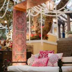 A cozy seating nook from a Kashmiri Sufi themed Mehfil. The design featured a traditional diwan, rich textiles, bolster cushions with intricate patterns, and hanging floral strings.
