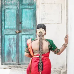 A beautiful shot from behind, highlighting the intricate bridal hairstyle and the stunning embroidery on the blouse, set against a rustic blue door.