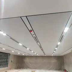 A view of a soundproof ceiling during installation. The fabric-finished panels are designed to absorb sound, and we've integrated linear lighting and air vents for a clean, seamless look.