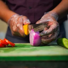 Freshness starts with the ingredients. Here, one of our chefs is carefully slicing fresh vegetables, a fundamental step in our process of creating delicious and healthy meals.