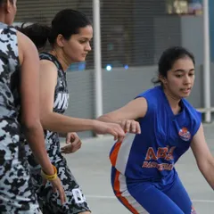 A young player from our girls' program focuses on her dribble while being guarded in a competitive match. We emphasize fundamental skills and court awareness in real-game situations.