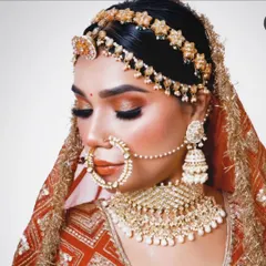 A stunning close-up of a bride wearing a full jewellery set, including a beautiful floral matha patti and a heavy pearl-drop choker.