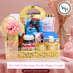 For the happy couple, I craft wedding hampers filled with blessings and indulgence. This beautiful hamper in a golden acrylic basket includes everything from Nutella and Raffaello to other premium treats, all elegantly packed.