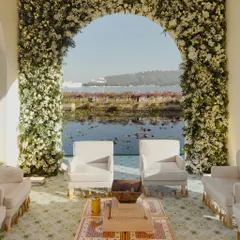 A serene mandap setting at the water's edge, framed by a lush arch of white flowers. This design creates a picture-perfect moment, blending the sacred space with the tranquil beauty of the lake.