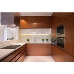 A U-shaped modular kitchen with rich, wooden cabinetry and built-in appliances. The design maximizes counter space and storage, making it highly efficient for everyday cooking.
