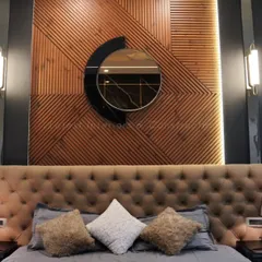 A close-up of the statement headboard, featuring a tufted suede finish and a unique wooden panel with a circular mirror. This detail adds a bespoke, artistic touch to the room.