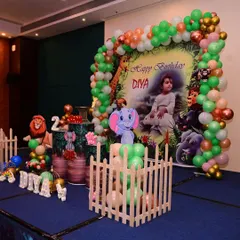 For this jungle-themed birthday, I created a full stage setup with a personalized backdrop, a green and orange balloon arch, and large cutouts of animals like lions and elephants to make it immersive.