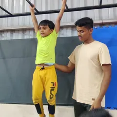 Our coaches provide hands-on support and encouragement for every child. Here, an instructor assists a young student with his monkey bar training, ensuring he builds strength safely.