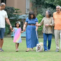 A multi-generational family strolls through a park with their dog. Outdoor lifestyle sessions like this are perfect for capturing natural interactions and candid moments.