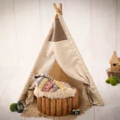 A cozy camping theme, with a newborn sleeping in front of a miniature teepee, complete with a tiny camera and lantern for a touch of adventure.