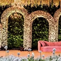 This reception stage features a backdrop of massive floral arches, creating a lush and romantic atmosphere. I work with expert florists to design and build large-scale floral installations for luxury wedding decor.