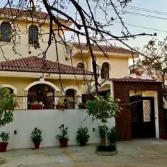 The Roopa Hariprasad Residence in Bangalore combines elements of traditional Indian and Mediterranean architecture. The design features arched windows, a tiled roof, and a prominent boundary wall to create a sense of privacy and timeless elegance.