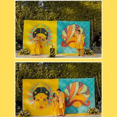 The couple poses against a quirky and colorful backdrop, showcasing the fun and personalized decor of their Haldi event.