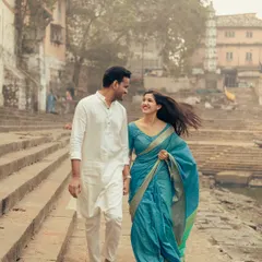 A happy, walking shot along the ghats, capturing the natural interaction and smiles between the couple in their traditional attire.