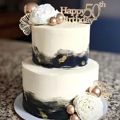 An abstract black and gold design for a 50th birthday celebration. This two-tier vanilla and butterscotch cake uses a modern, artistic buttercream technique, proving that milestone cakes can be both elegant and contemporary.