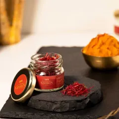 This shot shows the saffron both in its raw form and prepared as a paste. This helps customers understand the product's versatility and use in cooking, set against a warm and inviting background.