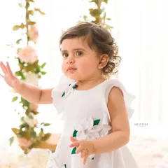 A curious and innocent portrait of a little girl reaching out. The soft, natural light highlights her delicate features and curly hair.