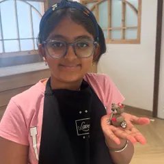 The proud smile of a little baker holding her finished creation. She made this adorable fondant teddy bear all on her own, from shaping the figure to adding the tiny heart. This is why I love teaching children.