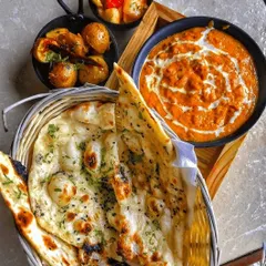 If you prefer to order exactly what you're craving, my à la carte menu is for you. Here you see our creamy Butter Paneer Masala served with hot, fluffy garlic naan and a side of spiced potatoes.