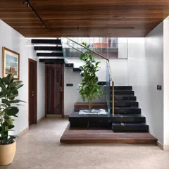 The cantilevered staircase, clad in black marble, is a central architectural feature of the duplex. I incorporated a small, skylit planter at its base, bringing a touch of nature indoors and creating a serene focal point.
