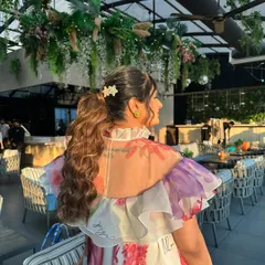 A voluminous curly ponytail for a baby shower. The cute star-shaped clips add a sweet, personal touch to this happy and celebratory hairstyle.