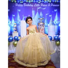 The daughter from a family I designed for, looking like a princess in her golden tulle gown at a royal-themed birthday party. Her dress was created to complement her parents' and brother's outfits.
