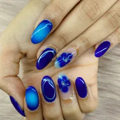 We treat every nail like a tiny canvas. This design showcases our skill in creating detailed floral art, featuring deep blue ombre effects and delicate, hand-painted flowers on almond-shaped extensions.