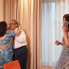 The beautiful chaos of getting ready. A bride on the phone while her parents share a hug in the background tells a real, multi-layered story.