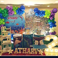 This underwater theme for Atharv's second birthday is full of fun sea creatures. The setup includes a shimmering sequin backdrop, whale and octopus cutouts, and a large marquee number '2'.