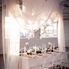 This image showcases how I use natural light and sheer drapes to create a soft, heavenly ambiance for a formal dinner. The all-white theme with minimalist floral accents is the epitome of modern elegance.