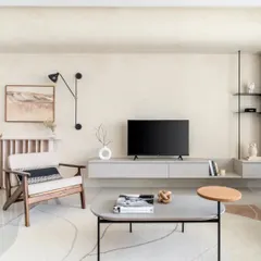 This living room from the SNN Raj Etternia project is a hideaway of grey, black, and cozy textures. A floating TV unit keeps the space feeling airy, while a statement accent chair and abstract art add personality.