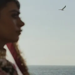 An artistic, out-of-focus shot of the bride's profile against the sea, with a bird flying in the distance. This poetic image captures the feeling of a seaside wedding in Mumbai.
