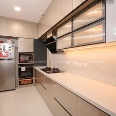 A sleek and modern kitchen with beige glossy cabinets and fluted glass overhead units. The design is clean, functional, and features a fully integrated hob and chimney.