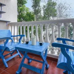 A charming balcony setup with bright blue foldable wooden chairs and a matching table. We help you create small outdoor retreats like this, perfect for enjoying a morning cup of tea.