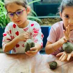 Two young artists fully engaged in sculpting their own Ganesha idols from clay. It's a wonderful, hands-on way to connect with the festival.