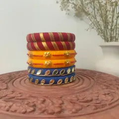 This stack of thread bangles in red, yellow, and blue is a classic festive combination. The set includes different designs, from gota patti work to mirror embellishments.