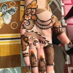 This is a beautiful example of an Arabic-style mehndi design. The pattern flows diagonally across the hand, using a mix of bold lines, delicate chains, and floral art.