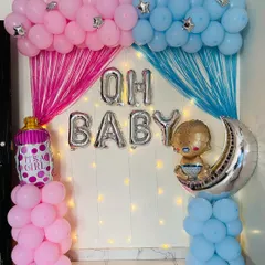 A classic "Oh Baby" gender reveal or baby shower decoration. The setup uses pink and blue balloons and streamers to represent a boy or girl, with foil balloons spelling out the message.