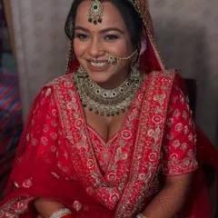 The smile of a happy Punjabi bride. Her look features classic winged eyeliner and a beautiful nath, paired with a stunning red lehenga.