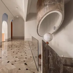 The staircase and galleria, showing the massive marble-clad light fixture that hangs from the ceiling, echoing the curve of the stairwell.