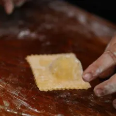 Sealing a single square of ravioli by hand. This close-up shows the care and attention that goes into each piece, promising a truly homemade taste for your guests.