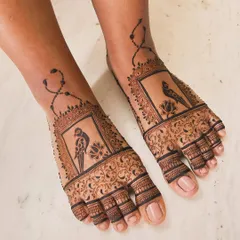 A unique and elegant feet design for an engagement. It features a parrot in a frame, with a delicate chain connecting to the ankle.