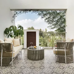 The balcony of the home office, with its patterned tiles and comfortable seating, offers a perfect spot for a break or an informal meeting.